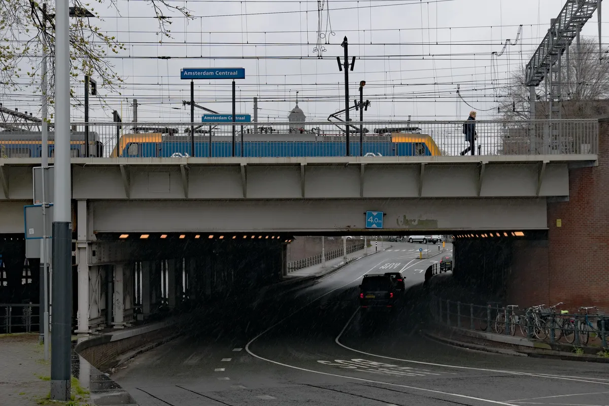 2023, Amsterdam photo - train bridge over the canal Westertoegang, on a gray day. Location is the West side of Central station Amsterdam. Street photography of The Netherlands by Fons Heijnsbroek - free photo in high resolution, CCO