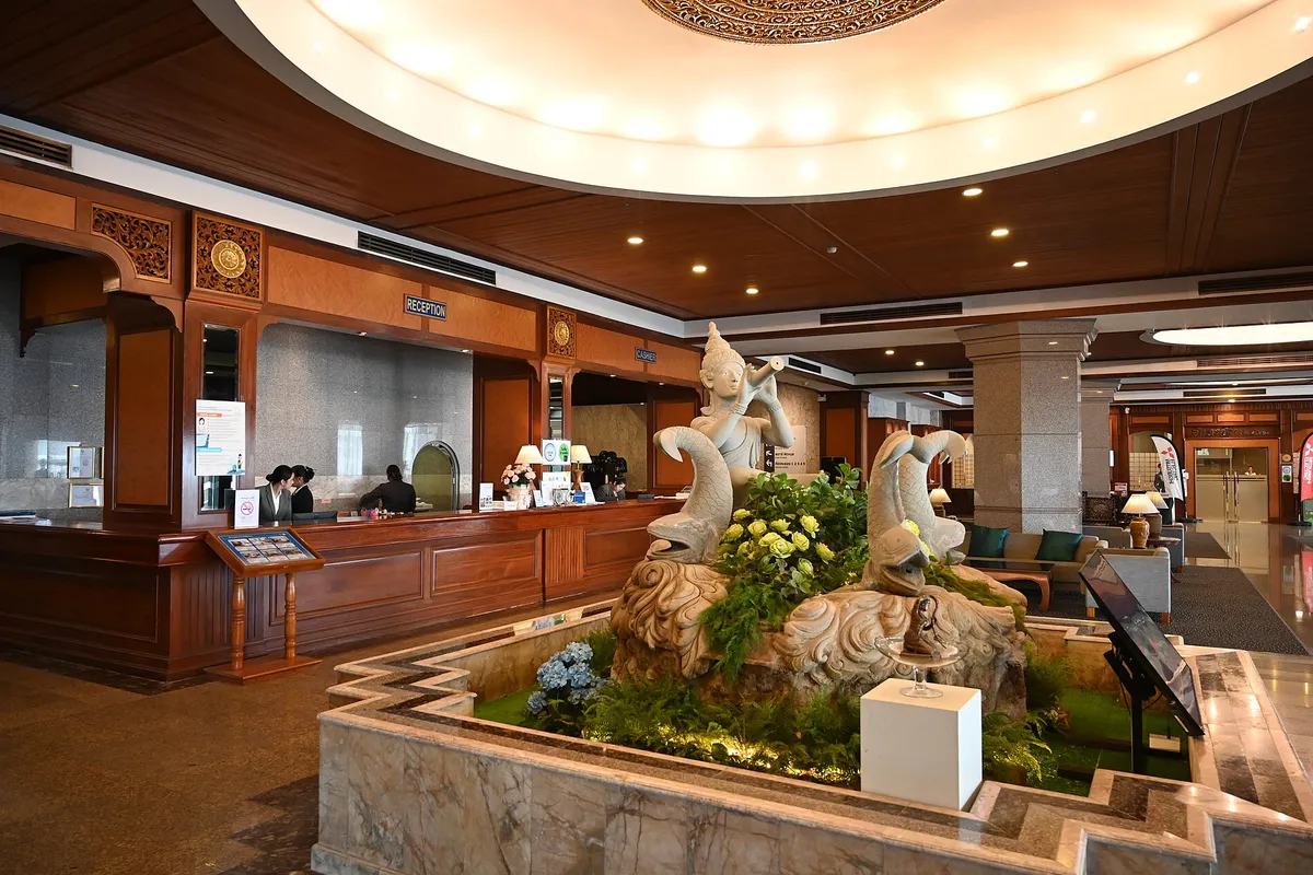 DZ6 0471 Luxurious hotel lobby with a carved stone fountain centerpiece polished wood reception desk and warm ambient lighting